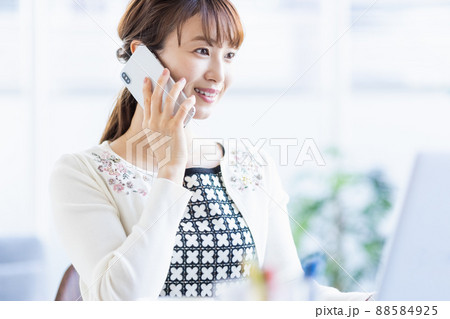 ノートパソコンを開いてスマホで通話する女性 ノートパソコンを開いてスマホで通話する女性 88584925