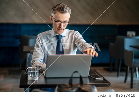 A businessman working on a laptop in a cafe A businessman working on a laptop in a cafe 88587419