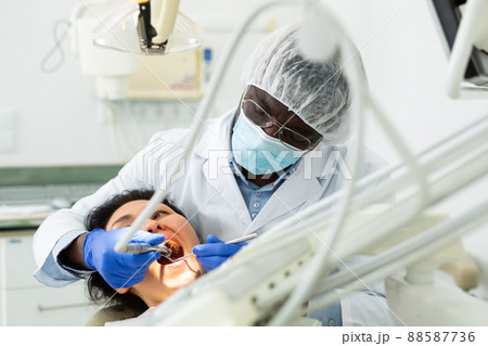 Male dentist using tools for tooth repairing on woman patient 88587736