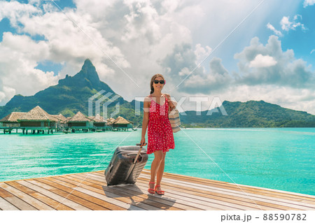 Hotel luxury resort tourist woman arriving with luggage suitcase in Tahiti Bora Bora honeymoon vacation travel on arrival deck at overwater bungalows 88590782