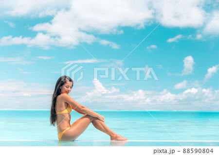 Spa body wellness therapy Asian beauty swimsuit model woman on luxury pampering thalasso pool resort relaxing sunbathing, sun tan skincare. Blue ocean sky background 88590804