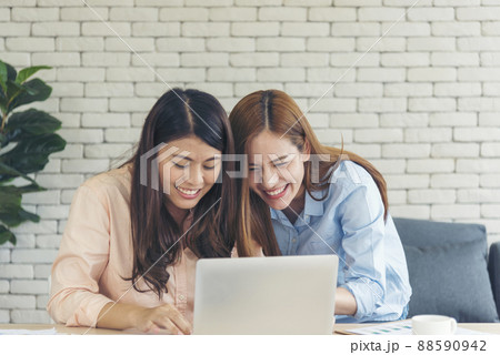 Asian colleague friendship at work with smiling face. Happiness two women colleague working together team meeting in office desk. Team business partners working with computer laptop startup company Asian colleague friendship at work with smiling face. Happiness two women colleague working together team meeting in office desk. Team business partners working with computer laptop startup company 88590942