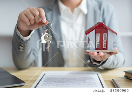 Insurance concept the real estate representative holding a house key on the right hand and the house model on the left hand 88590969