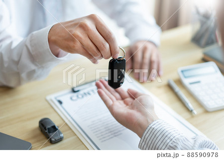 Insurance concept the customer receiving the car key after finishing the contract of car purchasing Insurance concept the customer receiving the car key after finishing the contract of car purchasing 88590978