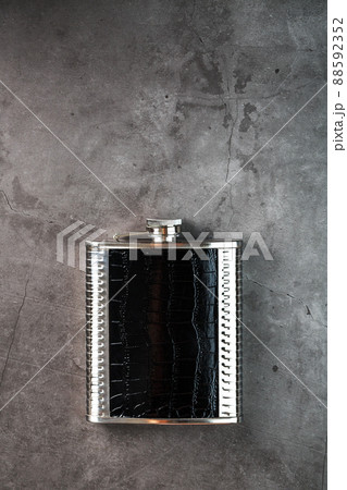 Steel flask in leather finish for alcohol on a dark background with copy space Steel flask in leather finish for alcohol on a dark background with copy space 88592352