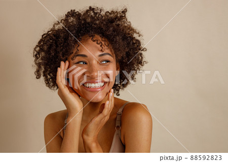Attractive multiracial woman posing at camera over beige background 88592823