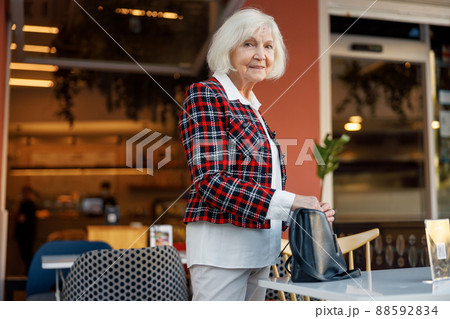 Positive retired woman smiling while standing outdoors Positive retired woman smiling while standing outdoors 88592834