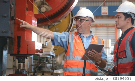 Engineer teaching apprentice to use metal sheet stamping machine 88594655