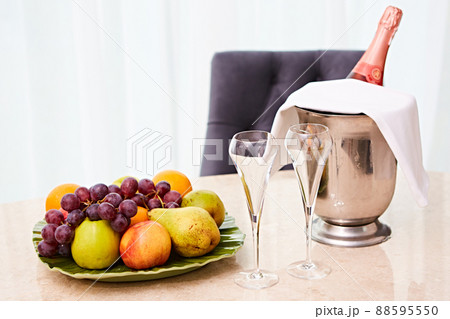 Champagne in a Hotel Room, Ice Bucket, Glasses and Fruits on a Plate - Honeymoon Concept Champagne in a Hotel Room, Ice Bucket, Glasses and Fruits on a Plate - Honeymoon Concept 88595550