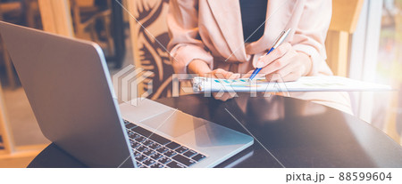 Woman analyzing data graph the stock situation.She uses a pen and a laptop computer. Woman analyzing data graph the stock situation.She uses a pen and a laptop computer. 88599604