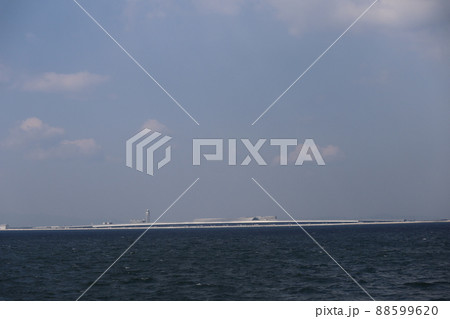 深く濃い青色の海面の海と空港のある人工島と雲と青空の見える風景 88599620