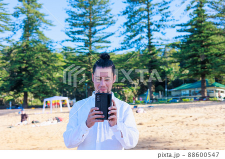 砂浜で写真を撮るラテン系男性 88600547