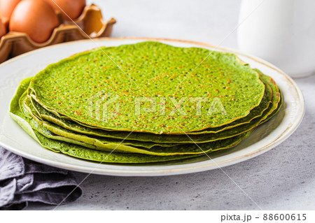 Stack of spinach crepes on plate. Green vegan pancakes, gray background. Healthy breakfast recipe. 88600615