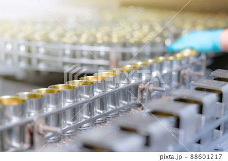 Canned fish factory. Food industry. Canned food factory. Sardines in tin cans. Food processing production line. Food manufacturing industry. Many can on a conveyor belt and blurred worker hand. 88601217