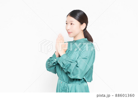 白い背景の前で掌を合わせてお願いする主婦 白い背景の前で掌を合わせてお願いする主婦 88601360