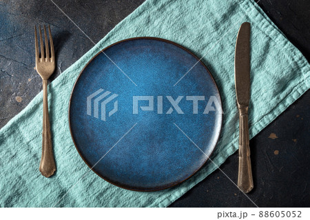 Cutlery with a blue plate. A fork, a knife, and a dish on a teal napkin Cutlery with a blue plate. A fork, a knife, and a dish on a teal napkin 88605052