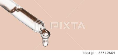 Cosmetics dropper, falling drop close up. Closeup of cosmetic pipette with essential oil dropping, serum with peptides on beige background. Beauty skin care product. 88610864