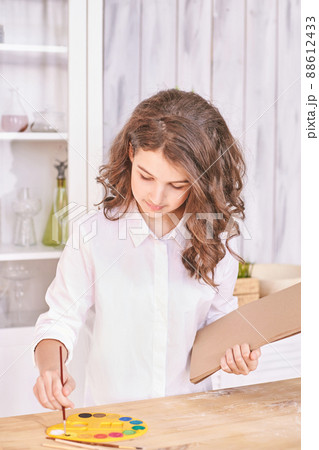 Young girl at paint studio portrait. Curly pretty child. Student looking tablet 88612433