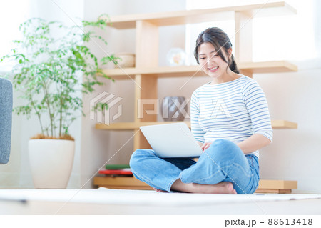 リビングでノートパソコンをする若い女性 リビングでノートパソコンをする若い女性 88613418