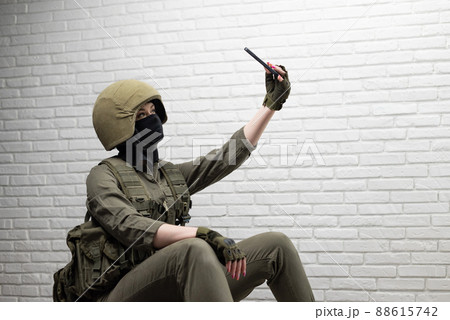a soldier girl in a helmet takes a selfie on a mobile phone a soldier girl in a helmet takes a selfie on a mobile phone 88615742