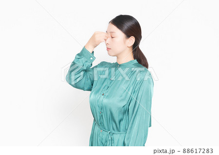 白背景の前に立って目頭をつまむ主婦 88617283