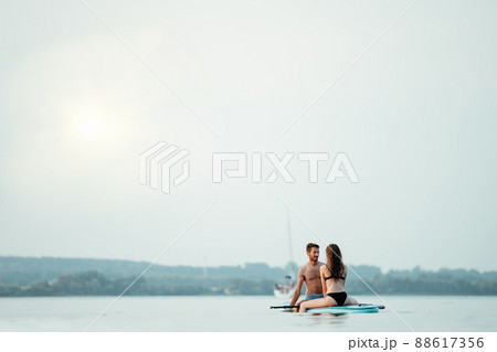 young couple in love is kissing sitting on the SAP board . young couple in love is kissing sitting on the SAP board . 88617356