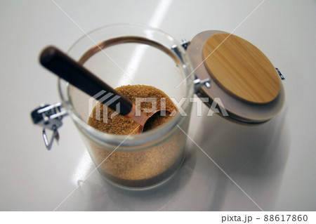 Close up of a isolated glass and wood cane sugar jar with a copper and wood spoon Close up of a isolated glass and wood cane sugar jar with a copper and wood spoon 88617860