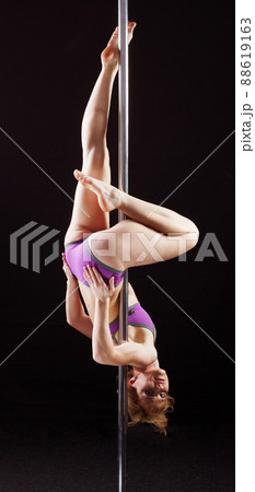The strong and graceful young girl performing acrobatic exercises on pylon 88619163