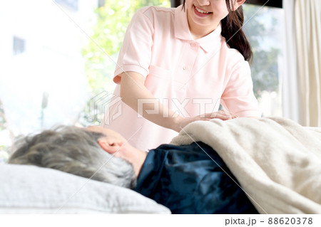 高齢者をベッドで介助する女性介護士 88620378
