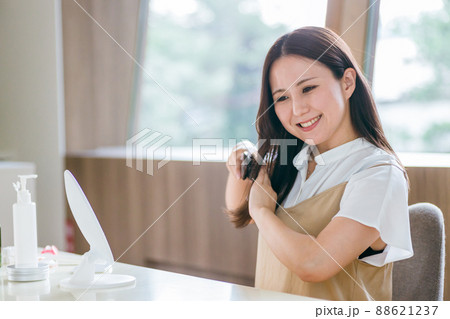 ヘアブラシで髪をとかす女性（笑顔） 88621237