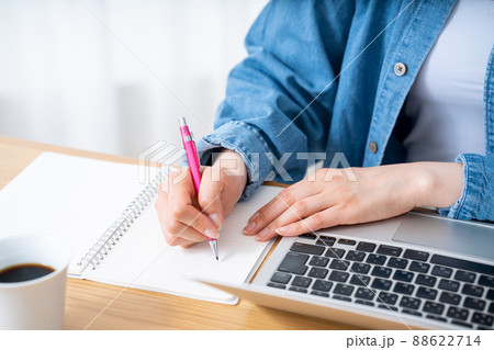 メモをとりながらノートパソコンを使う女性の手元【パーツカット】 88622714