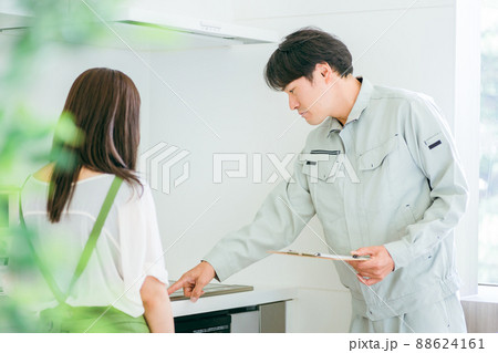 キッチンで話す作業着姿の男性と女性（IH） 88624161