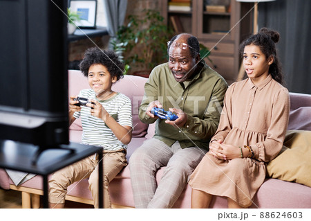 Group of happy grandchildren and their grandfather playing leisure games Group of happy grandchildren and their grandfather playing leisure games 88624603