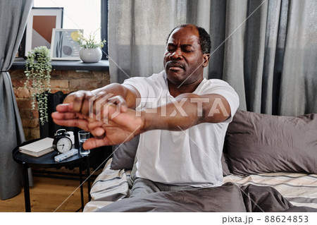 Active senior man doing sit ups right after sleep while sitting in bed 88624853