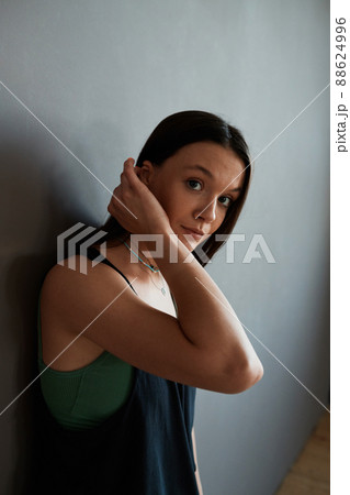 Young contemporary woman in black tanktop touching her dark long hair Young contemporary woman in black tanktop touching her dark long hair 88624996