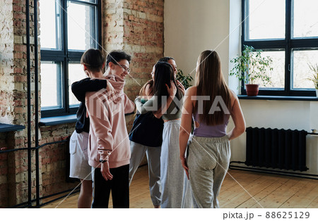 Group of happy teenagers giving hugs to one another before repetition in studio 88625129