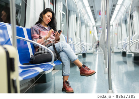 Woman passenger using phone in subway car Woman passenger using phone in subway car 88627385