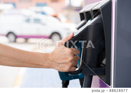 Unrecognizable Asian woman holding aa DC - CCS type 2 EV charging connector at EV charging station, woman preparing an EV - electric vehicle charging connector for recharge a vehicle. 88628977