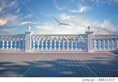 White decorative fence with columns on the seashore and seagull in sky 88631415