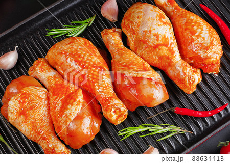 Background of meat with spices.Barbeque marinated chicken dramsticks on a black cooking board on a black background with fresh rosemary leaves. Semi-finished product, Marinated product,cooking. Background of meat with spices.Barbeque marinated chicken dramsticks on a black cooking board on a black background with fresh rosemary leaves. Semi-finished product, Marinated product,cooking. 88634413