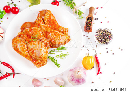 Barbecue marinated chicken dramsticks black culinary board,white background with fresh rosemary leaves and cherry tomatoes,various spices,close-up.Semi-finished product,quick cooking.Baner of meat. 88634641