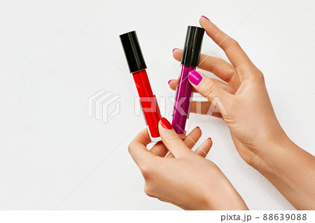Female hands with lip glosses isolated on white. Woman holding Red and Pink lip glosses. Space for text 88639088