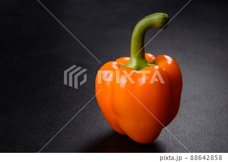 Fresh beautiful bell pepper orange on a dark concrete background Fresh beautiful bell pepper orange on a dark concrete background 88642858