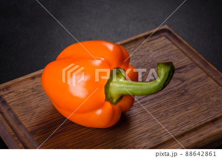Fresh beautiful bell pepper orange on a dark concrete background Fresh beautiful bell pepper orange on a dark concrete background 88642861