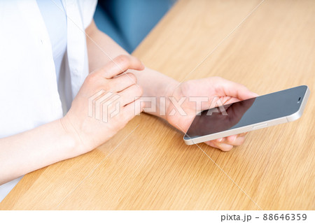 テーブルでスマホを使う女性の手元【パーツカット】 テーブルでスマホを使う女性の手元【パーツカット】 88646359