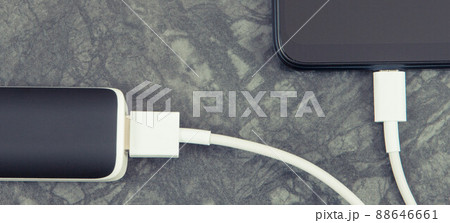 Black smartphone with connected plug of external powerbank. Mobile phone charging Black smartphone with connected plug of external powerbank. Mobile phone charging 88646661