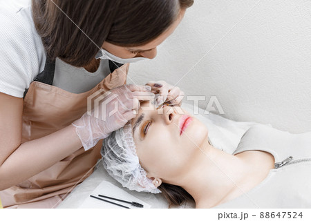 Young woman undergoing procedure of eyelashes lamination in beauty salon Young woman undergoing procedure of eyelashes lamination in beauty salon 88647524