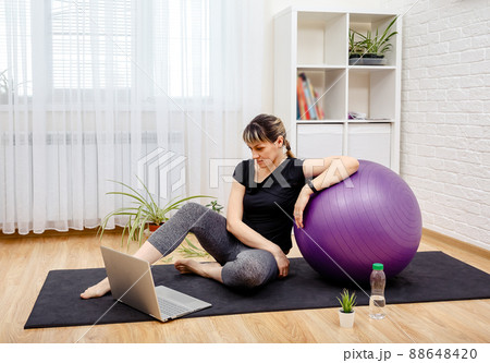 Sporty young woman sitting on yoga mat. Activity during quarantine. Sporty young woman sitting on yoga mat. Activity during quarantine. 88648420