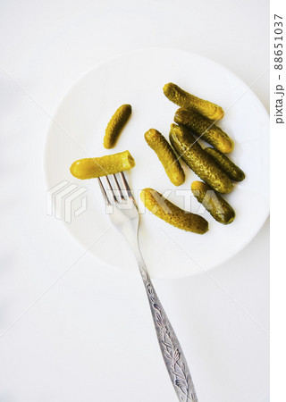 Green pickles on a white plate and a fork Green pickles on a white plate and a fork 88651037