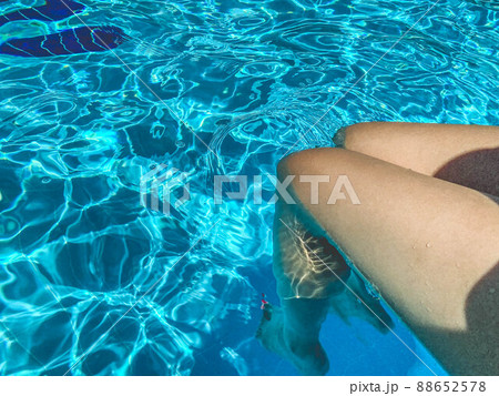 Hispanic woman's legs relaxing in swimming pool. 88652578